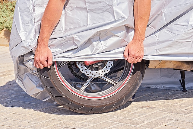 バイクにカバーをする画像